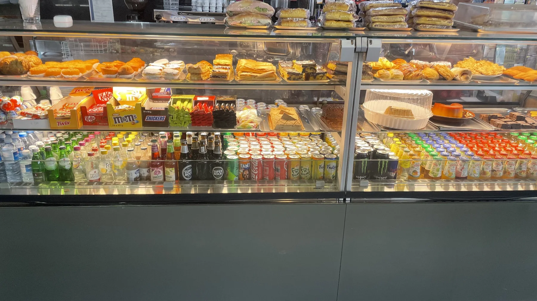 Balcão do Café dos Mogos com pastelaria, sandes e bebidas